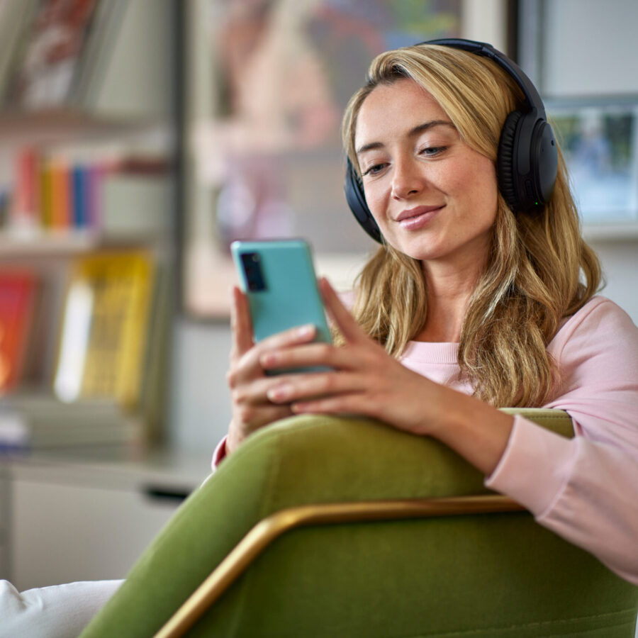 Blond woman wearing a headphone, going through her phone